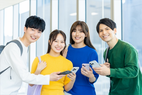 スマホを手に持っている4人の学生